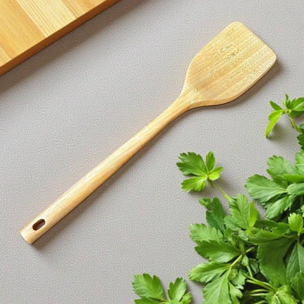 Bamboo Wooden spatula on a gray surface with green herbs