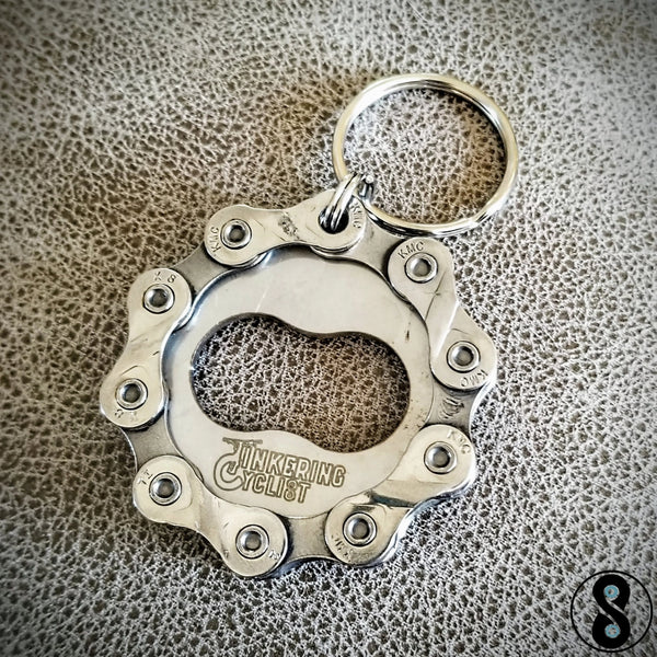 Metallic keychain with bottle opener on a textured surface