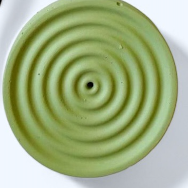 Green ceramic incense holder with concentric circular design on a white background