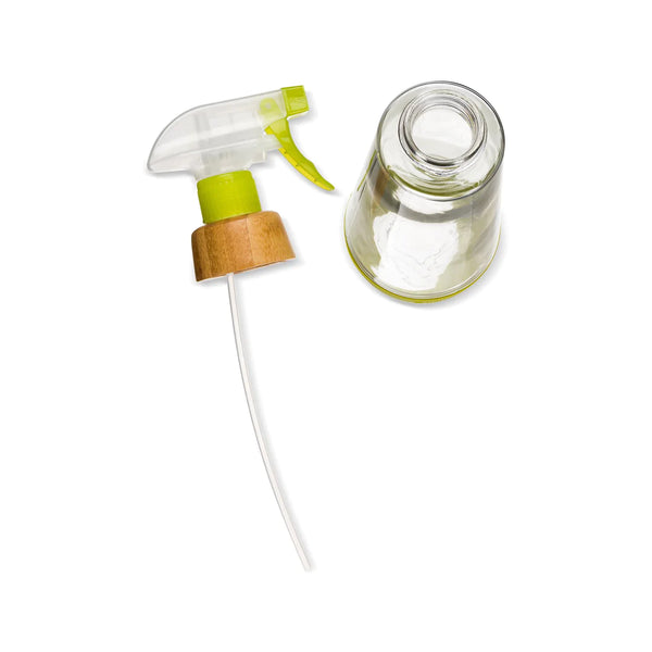 clear glass spray bottle with a green & clear plastic nozzle, bamboo collar, and green silicone bottom.Spray nozzle is shown taken off of the bottle. white background